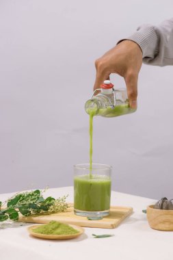 Yeşil çay beyaz masada cam çay bardağına dökülüyor