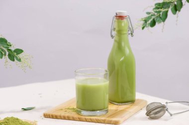 Beyaz arka plan üzerinde şişe ve fincan cam Matcha yeşil çay latte