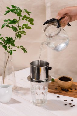 Damla, Brewing, koyu ahşap tahta üzerinde Vietnam Phin Filtre bulunan öğütülmüş kahve üzerine su dökme. Seçici Odak.