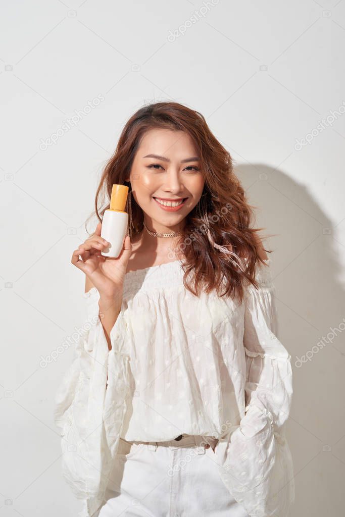 smiling young woman showing skincare products