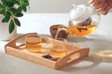 Ahşap servis tepsisinde cam Çaydanlık bir el çay dökme