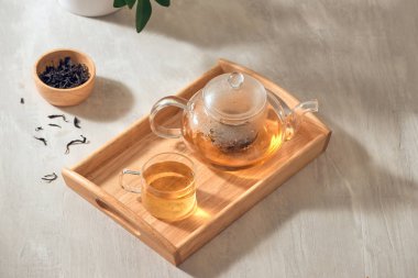 Ahşap bir arka planda şeffaf bir fincan ve çaydanlık çay