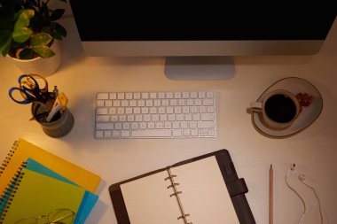 Bilgisayar, sarf malzemeleri, bitki ve kahve fincanı ile ofis masası