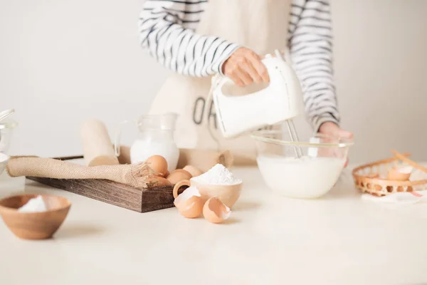 Mixing white eggs cream in bowl with motor mixer, baking cake