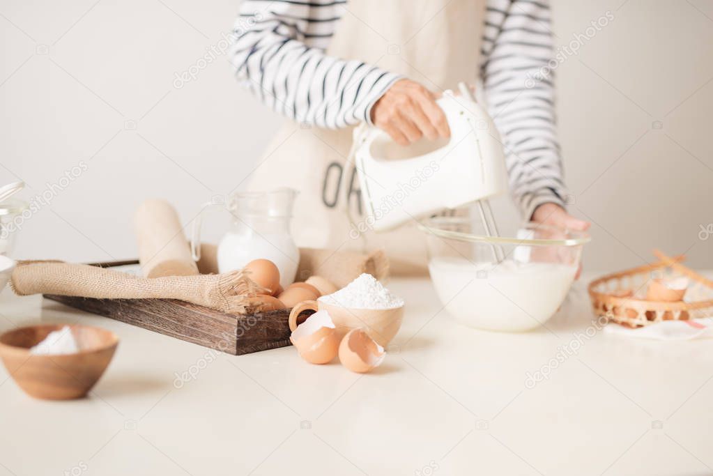 Mixing white eggs cream in bowl with motor mixer, baking cake 