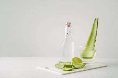 beyaz arka plan üzerinde taze aloe vera yaprakları ve cam şişe