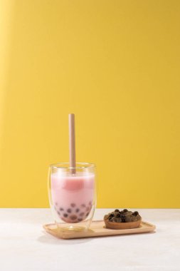 Çilek lezzet boba çay / sarı arka plan üzerinde tapyoka topu bir tabak ile buble çay