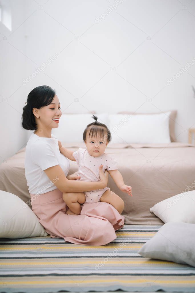 Young mother with her cute little baby at home