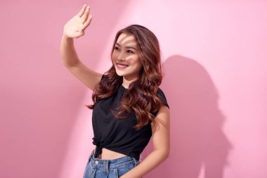 Genç ve güzel Asyalı kadın pembe arka planda izole edilmiş güneş ışığından korkuyor. Yazın cilt bakımı ve güneş ışığından korunma kavramı 