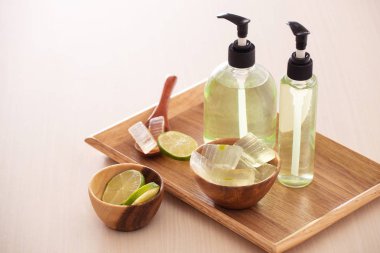 Aloe vera yaprağı, soyulmuş aloe, limon ve aloe jel veya infüzyon şişeleri dolu kase