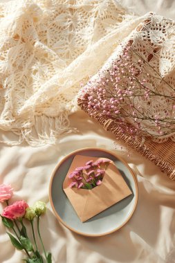 Zarf içinde çiçekler ve bardak ve kumaş arka plan üzerinde çay fincan ile taze çiçekler 