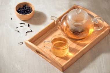 Ahşap bir arka planda şeffaf bir fincan ve çaydanlık çay