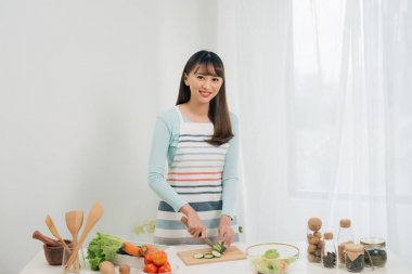 Genç kadın mutfakta sebze kesiyor. Kadın sağlıklı gıda pişirme. 