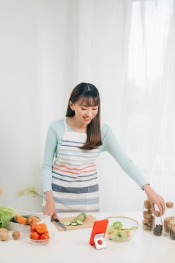 Mutlu kadın tarifi mutfakta tablet bakarak önlük. Sebze salatası. Diyet kavramı. Sağlıklı bir yaşam tarzı. Evde yemek. Yemek hazırlamak.