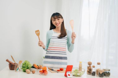 Güzel genç asyalı kadın yemek tarifi okuma veya salata yaparken göstermek izlerken