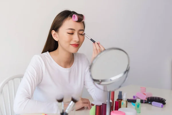 Attractive talented female blogger reviews beauty product for video blog, gives advice to girls and women, films process on camera.
