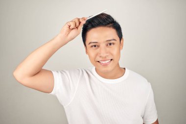 T-shrit'te gülümseyen adamın saçlarını tarayan portresi.