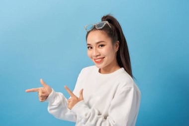 Fotoğraf muhteşem kadın gülümseyen ve işaret parmaklar kenara boşaltmak açık mavi arka plan üzerinde izole