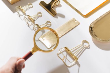 Işık arka planda altın kırtasiye üzerinde büyüteç tutan kadın