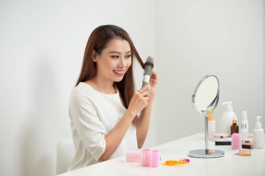 Düğüm kurtuluyorum. Güzel genç kadın soyunma masada otururken uzun saçları fırçalama mirrorand onun yansıması bakarak