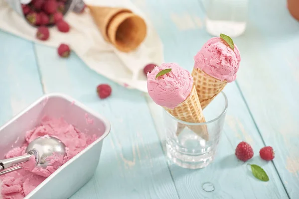 Homemade raspberry ice cream in waffle cones.