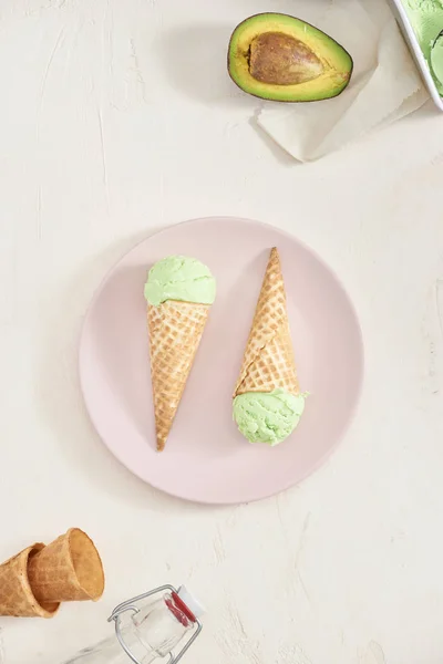 Green avocado ice cream scoops in wafle cones on white background. Copy space