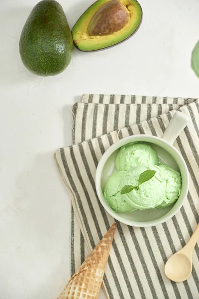 homemade organic avocado ice cream, with ice cream cones. On a grey stone table, copy space