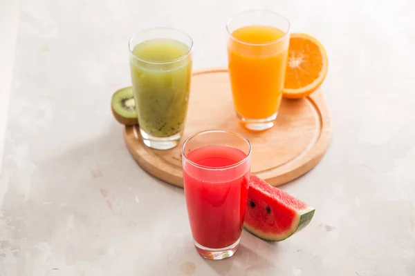 Свіжі Соки Згладжують Три Склянки Червоного Зеленого Апельсина Тропічні Фрукти — стокове фото