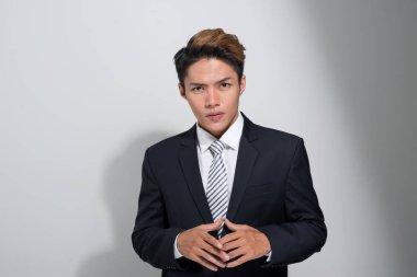 Beyaz arka plan üzerinde izole bir ceket tutan genç ve yakışıklı Asya iş adamı Portresi