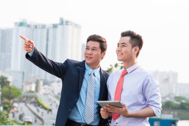 Genç yakışıklı işadamları dijital tablet bilgisayar açık havada proje tartışıyor