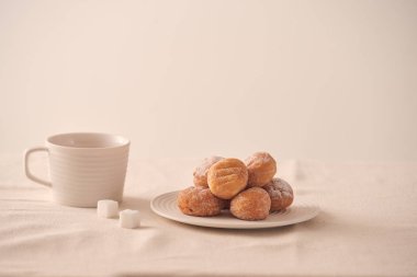 Tabakta şeker li çörekler ve beyaz arka planda kahve fincanı