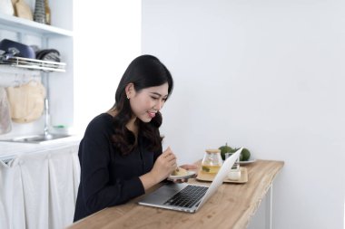 gülümseyen genç kadın mutfakta ev dizüstü kullanarak