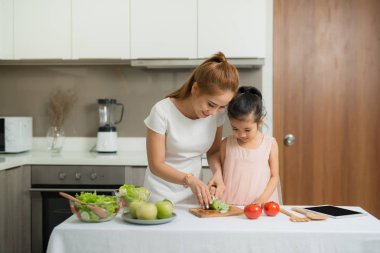 Mutlu anne ve kızı yapma ve sağlıklı yemek birlikte evlerinde sahip keyfini çıkarın