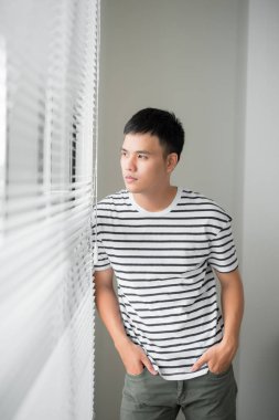 Mutlu Asyalı iş adamı bir ofis penceresinden dışarı bakıyor.