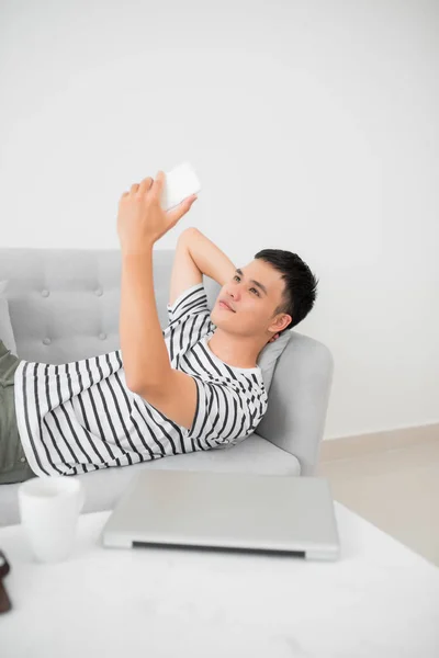 Asian Young Man Using Mobile Phone While Lying Indoor — Stock Photo, Image