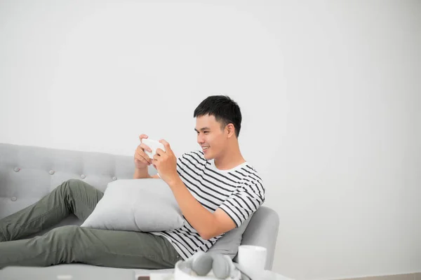 Asiático Jovem Homem Usando Telefone Celular Enquanto Deitado Interior — Fotografia de Stock
