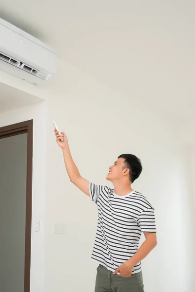 Air conditioner inside unit with man operating remote controller. / Air conditioner with remote controller