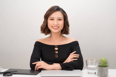 Asyalı bayan tasarımcı iş yerinde kameraya bakıyor. Kendine güvenen güzel bir kadın çalışırken dizüstü bilgisayarı ve grafik tabletiyle masada oturuyor. Yaratıcılık, sanat, iş dünyası, iş kavramı