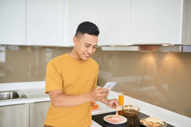 Cep telefonu tutan kahvaltı mutfak, otururken yakışıklı genç