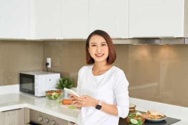 Güzel genç kadın mutfak tezgahı onun cep telefonu metin mesajı okuma ayakta.