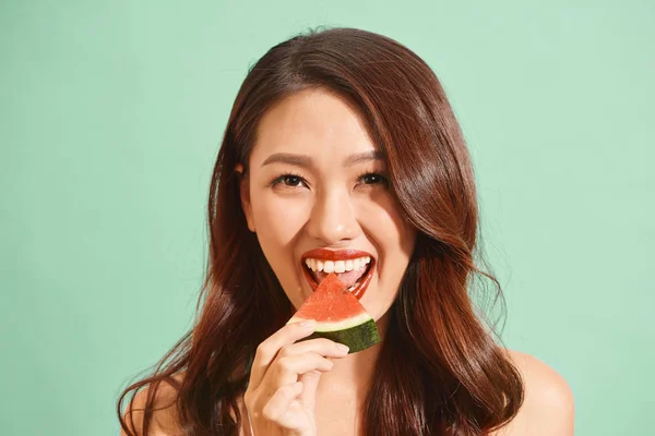 Pretty Asian woman eating a slice of watermelon in summer
