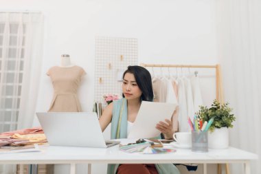 Atölyesi üzerinde çalışan genç bir Asyalı moda tasarımcısının portresi