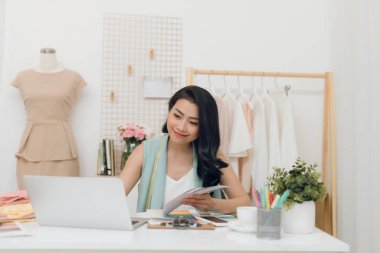 Atölyede bilgisayar kullanarak Güzel genç Asya iş kadını / moda tasarımcısı
