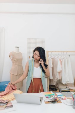 Moda trendlerini tartışıyoruz. Güzel genç kadın cep telefonu konuşuyor ve onu atölye ayakta iken dizüstü bilgisayar üzerinde çalışıyor