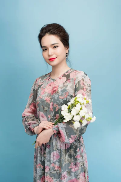 青い背景に立つ花のドレスで魅力的なアジアの女の子 — ストック写真