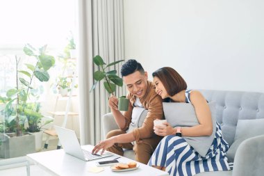 Bilgisayarlı mutlu çift evde vakit geçiriyor.