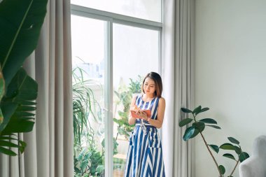 Genç Asyalı kadın kapı yakınında defter / günlük yazma. 