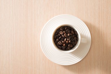 Ahşap arka plan üzerinde tam kahve çekirdekleri Fincan