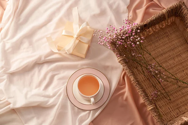 Tasse Tee Geschenkbox Und Blumen Auf Tablett Auf Hellem Stoff — Stockfoto
