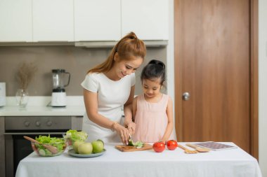 Mutlu anne ve kızı yapma ve sağlıklı yemek birlikte evlerinde sahip keyfini çıkarın